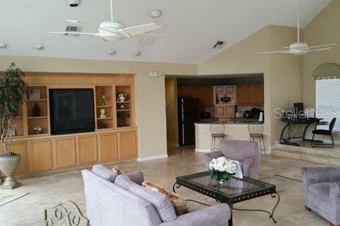 living room with lofted ceiling, ceiling fan, and built in shelves