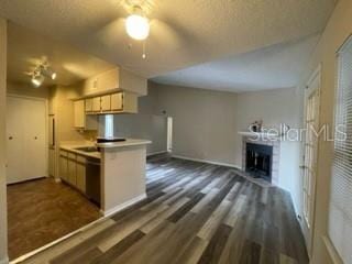 kitchen with dark hardwood / wood-style floors, ceiling fan, a fireplace, and kitchen peninsula