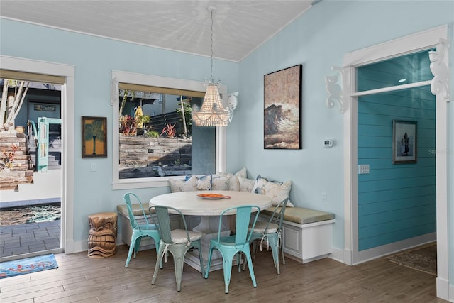 dining area with breakfast area, a notable chandelier, hardwood / wood-style flooring, and vaulted ceiling