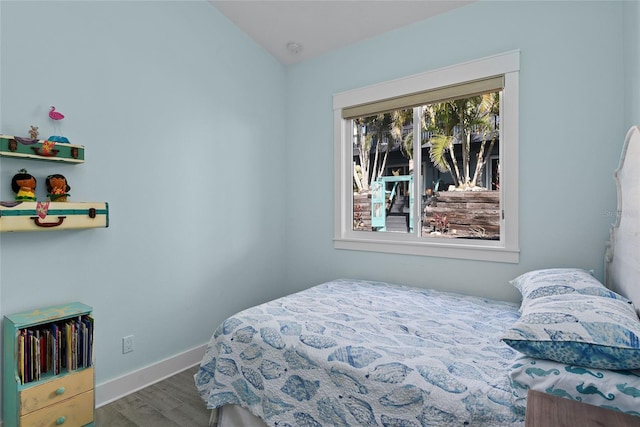 bedroom with hardwood / wood-style flooring and lofted ceiling