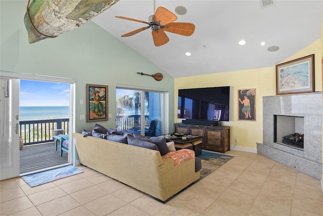 tiled living room with a water view, ceiling fan, plenty of natural light, and a fireplace