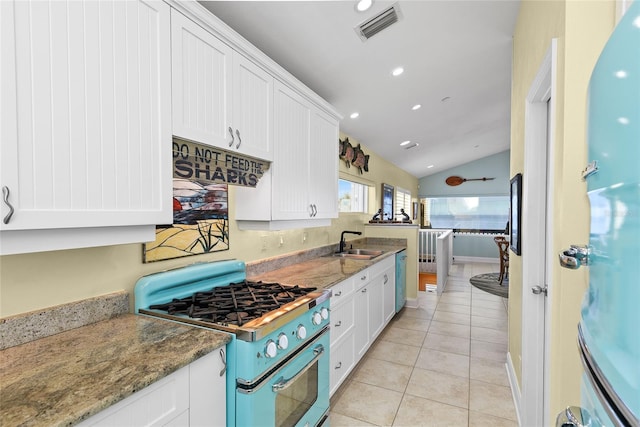 kitchen with white cabinetry, dark stone countertops, sink, and stove