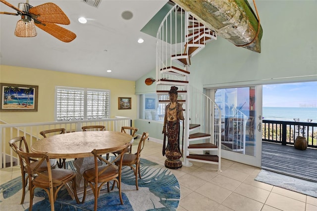 dining room with light tile patterned floors, high vaulted ceiling, ceiling fan, and a water view