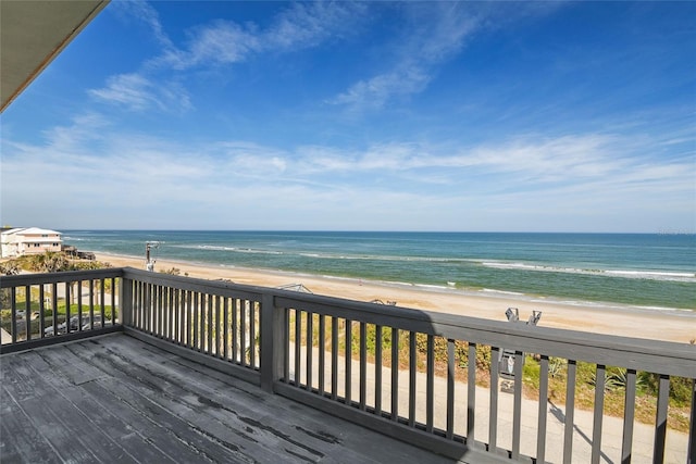 wooden deck featuring a water view and a beach view