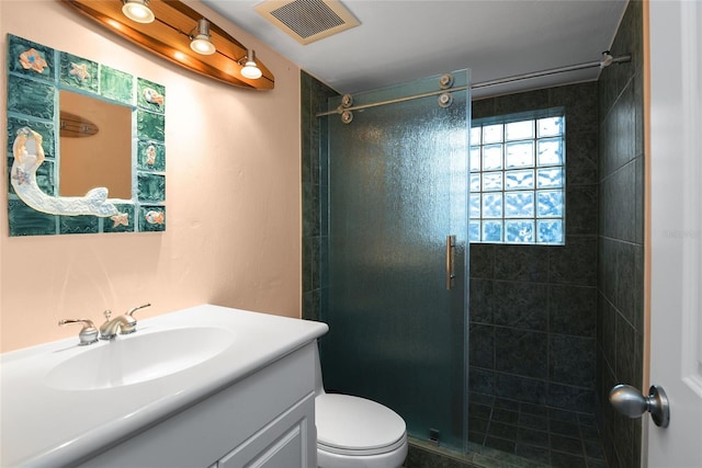 bathroom with vanity, a shower with shower door, and toilet