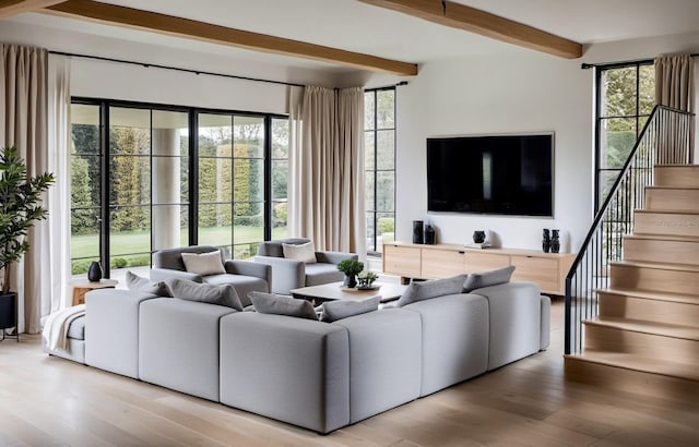 living room with beam ceiling, a healthy amount of sunlight, and light hardwood / wood-style floors