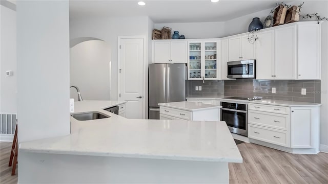 kitchen with stainless steel appliances, a kitchen island with sink, sink, and white cabinets