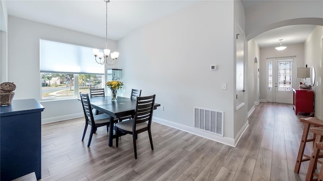 dining area with an inviting chandelier, plenty of natural light, and light hardwood / wood-style flooring