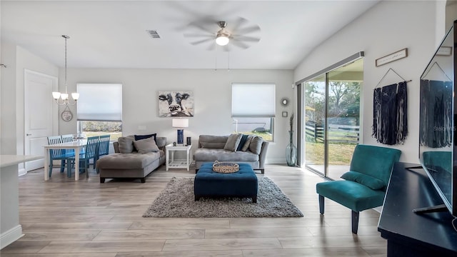 living room featuring ceiling fan with notable chandelier and light hardwood / wood-style floors