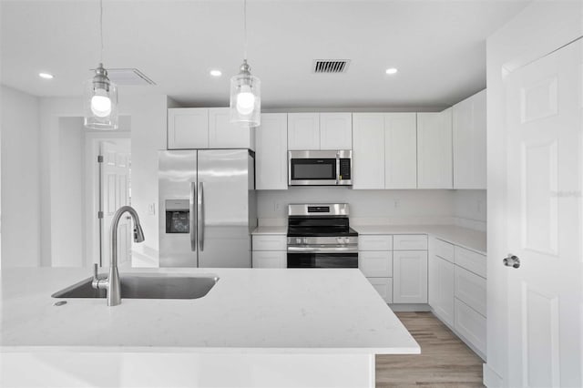 kitchen with sink, white cabinetry, light stone counters, decorative light fixtures, and stainless steel appliances