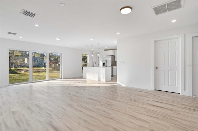 unfurnished living room with sink and light wood-type flooring