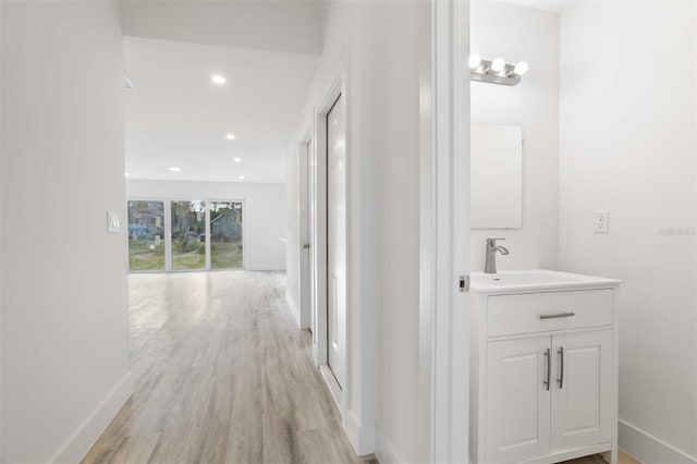 corridor with sink and light hardwood / wood-style flooring