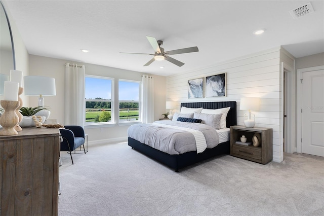 bedroom featuring wooden walls, light colored carpet, and ceiling fan