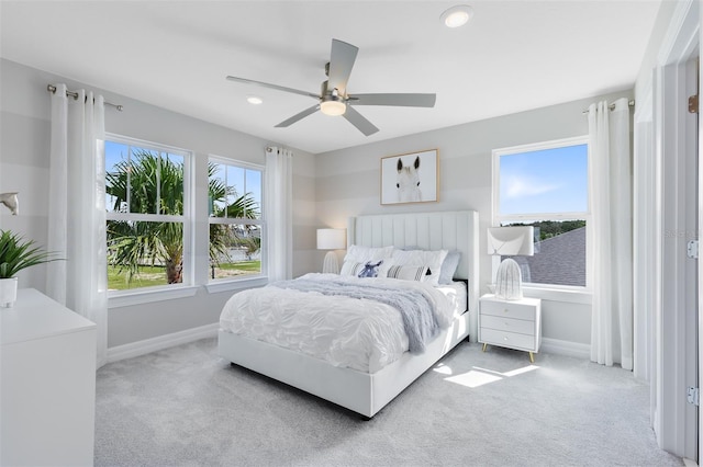 bedroom with light carpet, multiple windows, and ceiling fan