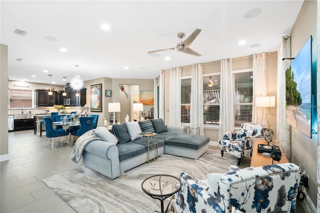 living room featuring plenty of natural light, sink, and ceiling fan with notable chandelier