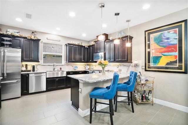 kitchen with a kitchen bar, sink, pendant lighting, stainless steel appliances, and decorative backsplash