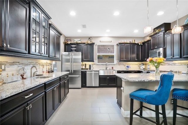 kitchen featuring stainless steel appliances, sink, dark brown cabinetry, and decorative light fixtures