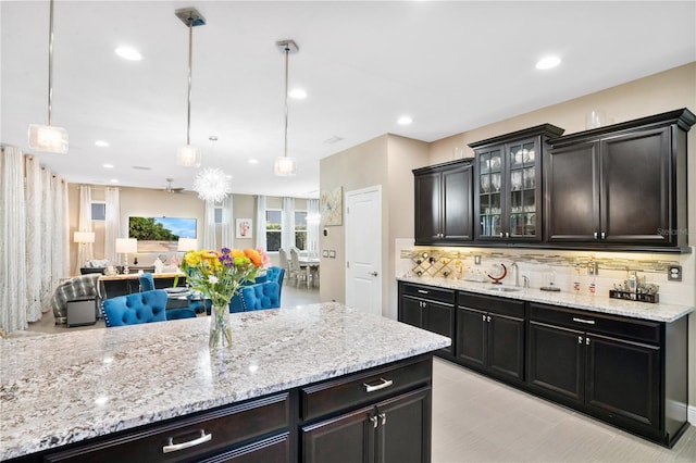 kitchen with sink, pendant lighting, light stone counters, and decorative backsplash