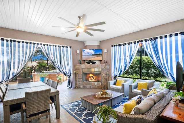 living room with ceiling fan, plenty of natural light, a fireplace, and concrete flooring