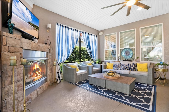 sunroom / solarium with a stone fireplace and ceiling fan