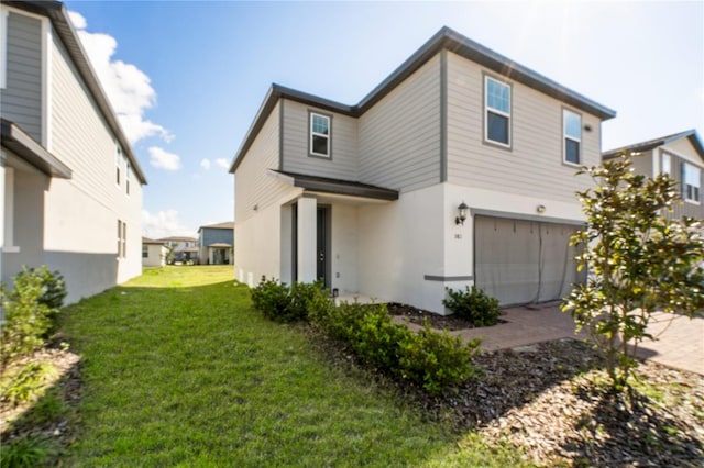 exterior space featuring a garage, driveway, a lawn, and stucco siding