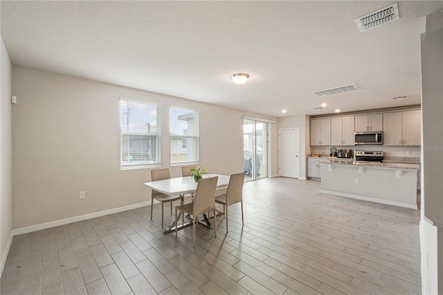 dining space featuring a wealth of natural light, light wood-style flooring, and visible vents