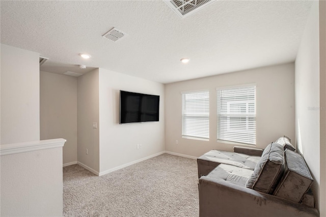 carpeted living room featuring baseboards, visible vents, and a textured ceiling