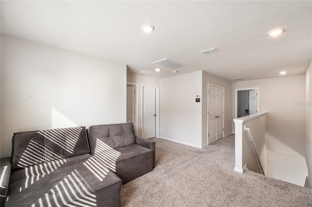 carpeted living area featuring recessed lighting, visible vents, and baseboards