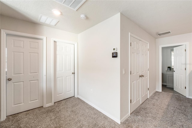 hallway with carpet flooring, visible vents, and baseboards