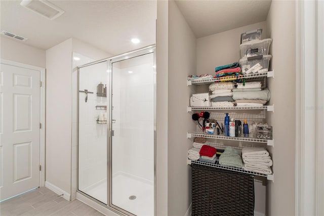 bathroom featuring visible vents, a shower stall, baseboards, and wood finished floors