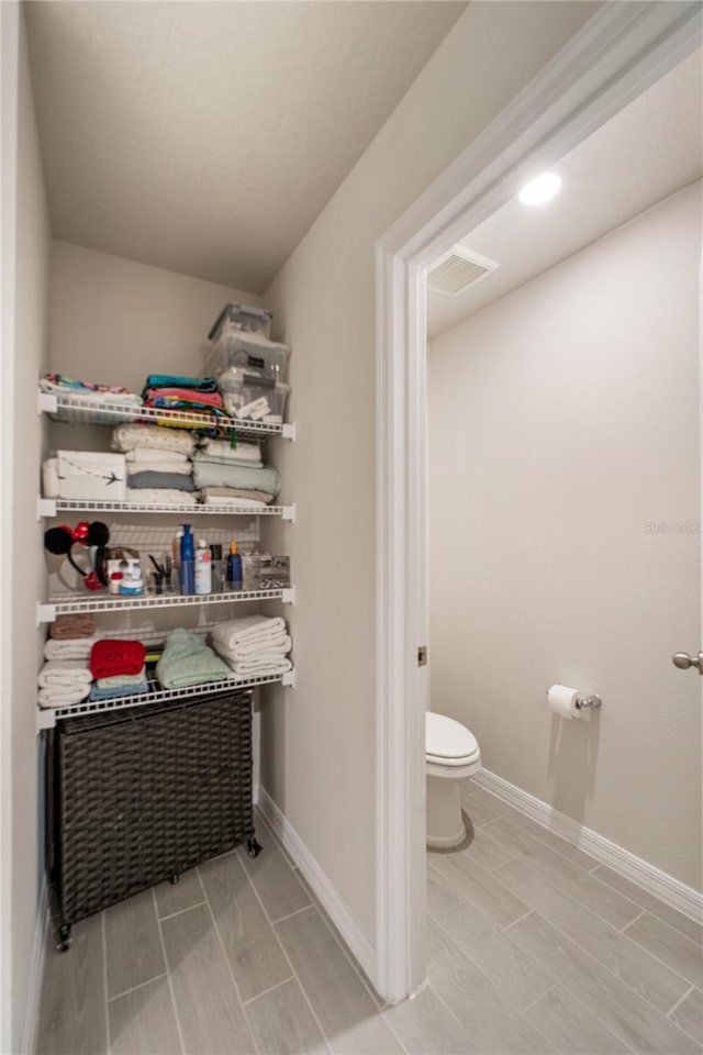 bathroom with wood finish floors, baseboards, and toilet