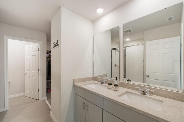 bathroom featuring visible vents, a sink, a shower stall, and a spacious closet