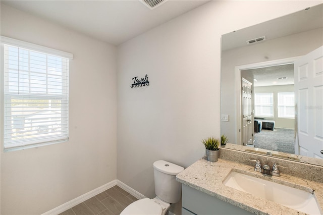 bathroom with visible vents, vanity, toilet, and baseboards