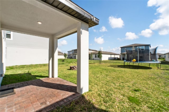 view of yard with a trampoline, a patio area, and a residential view