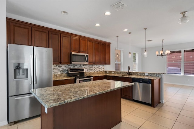 kitchen featuring appliances with stainless steel finishes, decorative light fixtures, sink, decorative backsplash, and kitchen peninsula