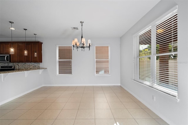 unfurnished dining area with light tile patterned flooring and an inviting chandelier