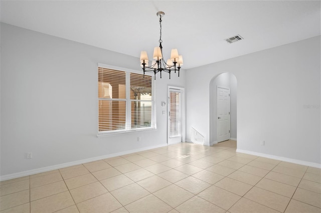 tiled spare room featuring a chandelier