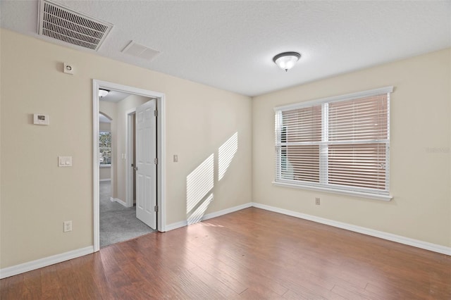 unfurnished room featuring hardwood / wood-style floors, a textured ceiling, and a healthy amount of sunlight