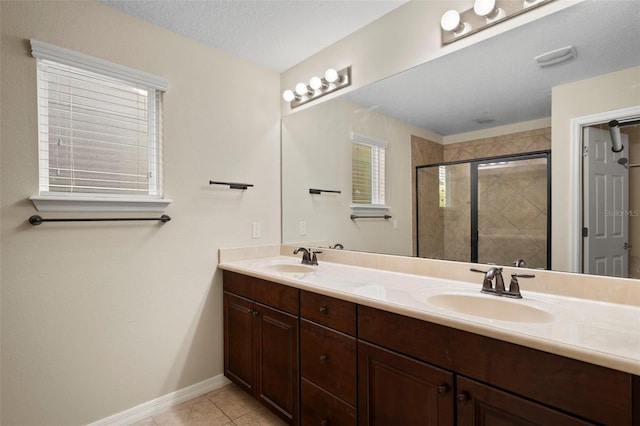 bathroom with a shower with door, vanity, tile patterned floors, and a textured ceiling