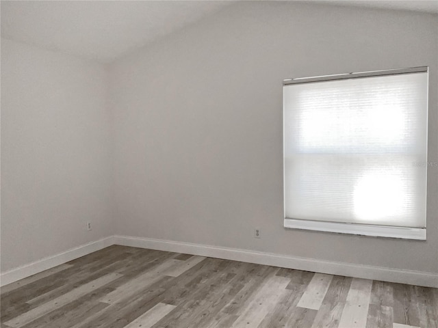 spare room with wood-type flooring and lofted ceiling