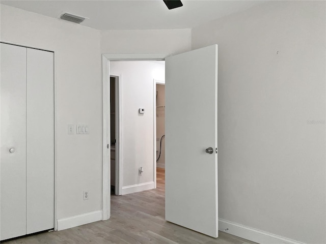 unfurnished bedroom featuring a closet, ceiling fan, and light wood-type flooring