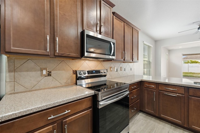 kitchen with tasteful backsplash, light stone counters, light hardwood / wood-style flooring, ceiling fan, and stainless steel appliances