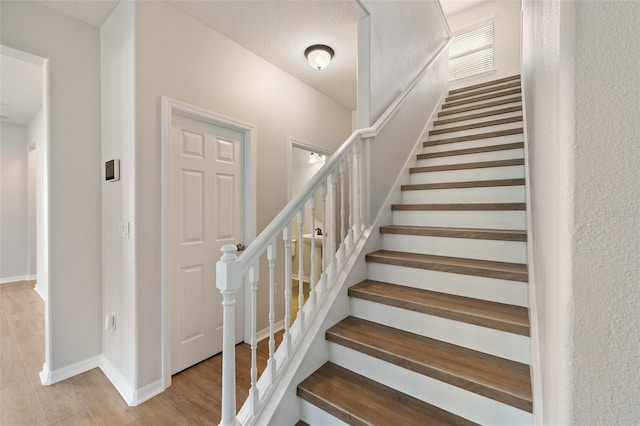 stairway with hardwood / wood-style flooring and a textured ceiling