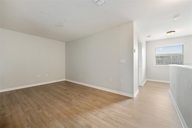 spare room featuring a textured ceiling and light hardwood / wood-style flooring