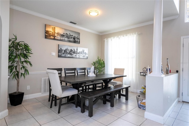 dining area featuring decorative columns, ornamental molding, and light tile patterned floors