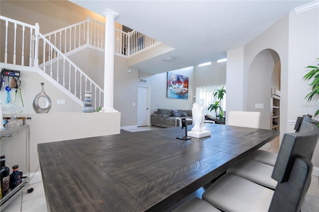 dining space with decorative columns, a towering ceiling, and light tile patterned floors