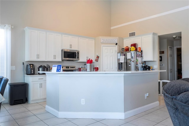 kitchen featuring white cabinetry, appliances with stainless steel finishes, a center island with sink, and a high ceiling