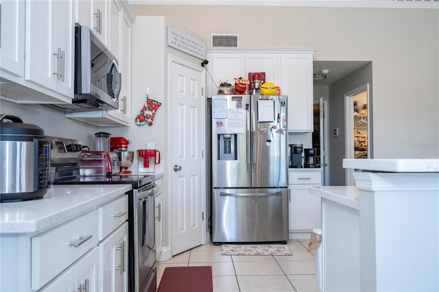 kitchen featuring white cabinetry, stainless steel appliances, light stone counters, and light tile patterned floors