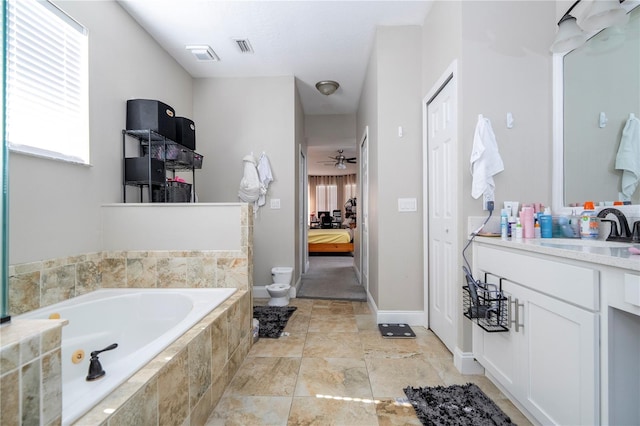 bathroom with ceiling fan, vanity, toilet, and tiled tub