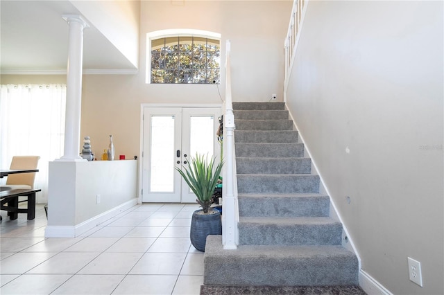 tiled foyer with french doors, a healthy amount of sunlight, and ornate columns